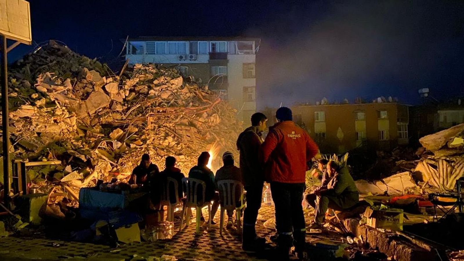 Un grupo de personas se calienta en una hoguera frente a unos escombros en Antioquia