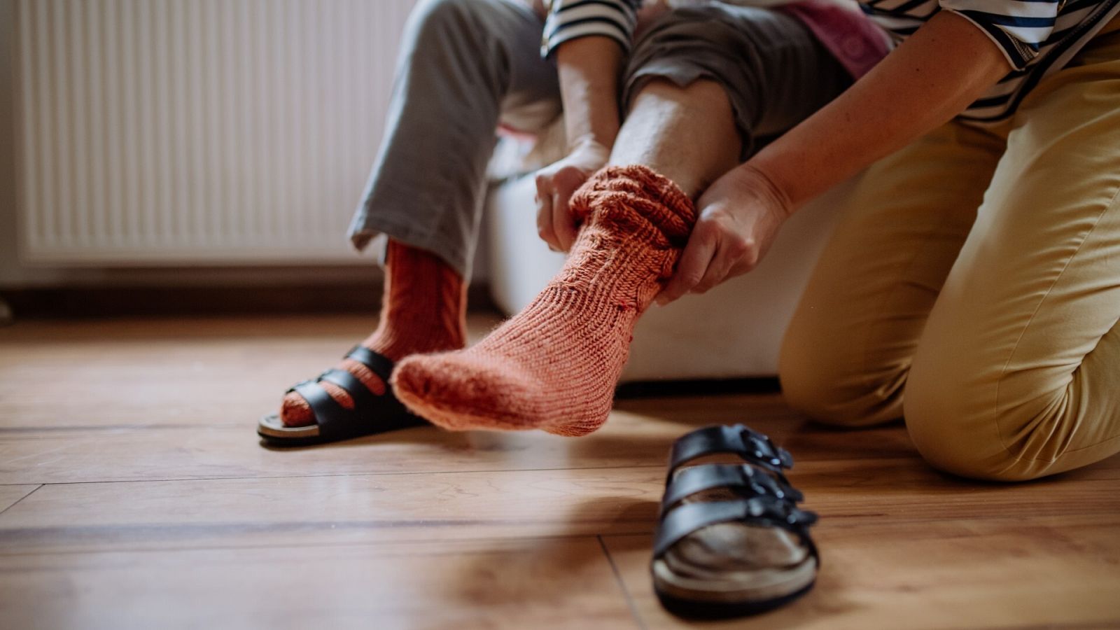 Día de la Mujer 2023: un mujer ayuda a una persona mayor a ponerse los calcetines