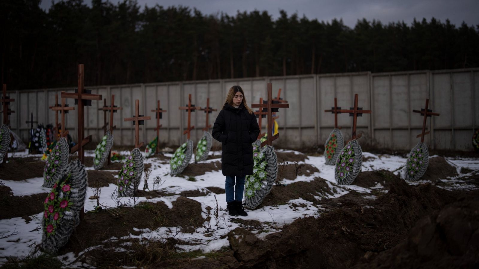 Una mujer de pie en el cementerio de Bucha, Ucrania