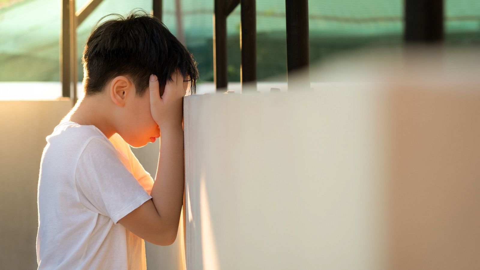 Suicidio y acoso escolar: un niño se tapa la cara con las manos