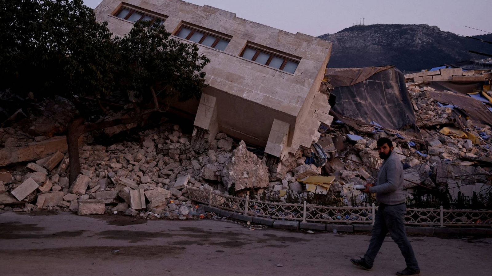Un hombre caminando por delante de un edificio derrumbado en Antioquía, Turquía.