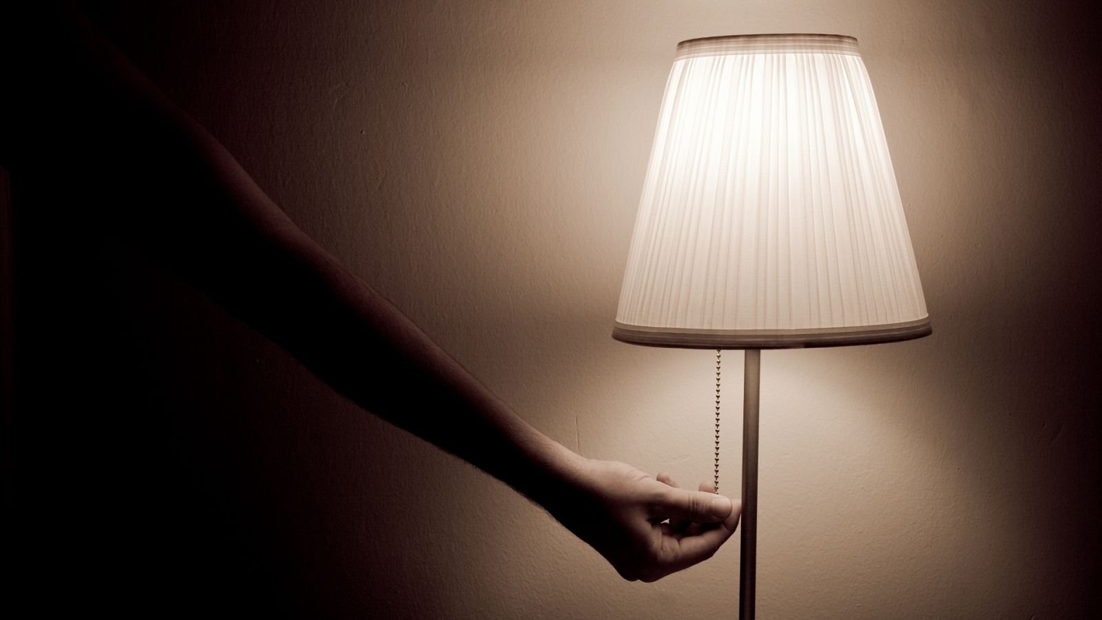 Una persona enciende una lámpara en su vivienda