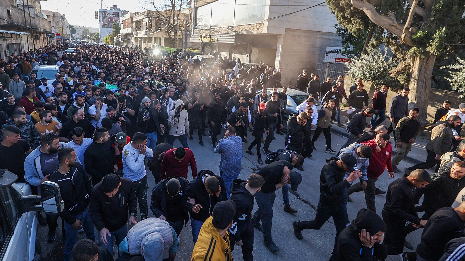 Hombres armados disparan al aire mientras los manifestantes llevan los cuerpos de los palestinos muertos durante la incursión israelí