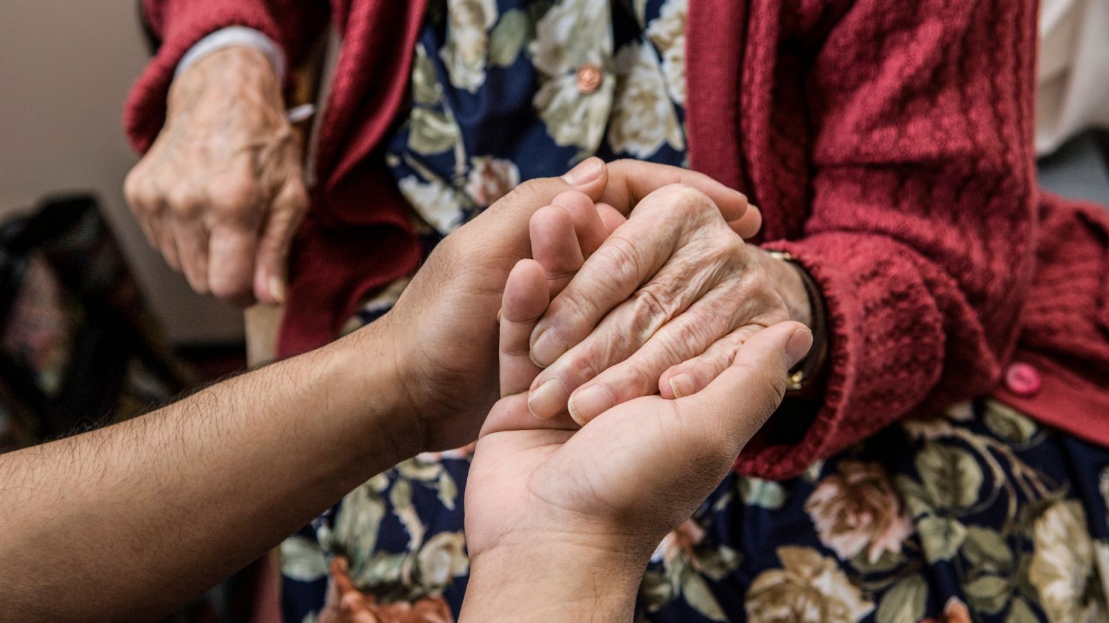 Una persona sostiene la mano de una mujer anciana