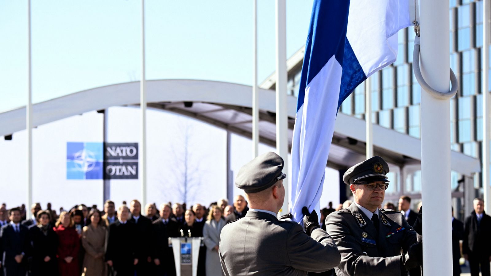 Militares finlandeses izan la bandera de Finlandia en la sede de la OTAN, en Bruselas