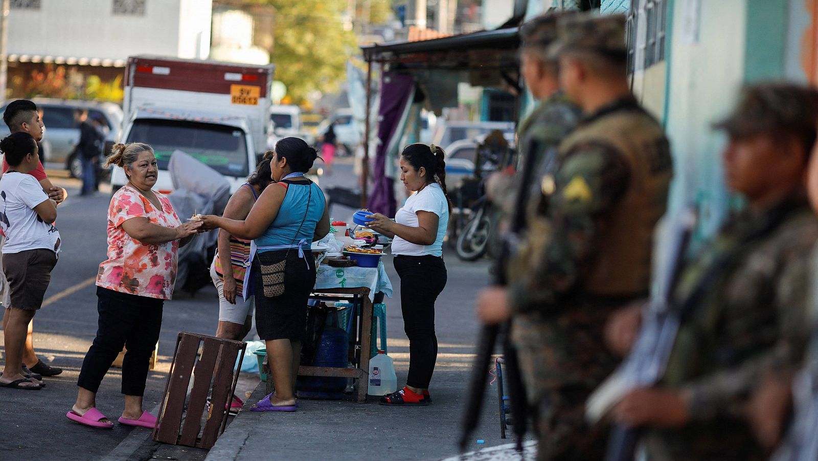 Varias mujeres venden bocadillos en una calle del barrio de Las Margaritas durante una patrulla antipandillas