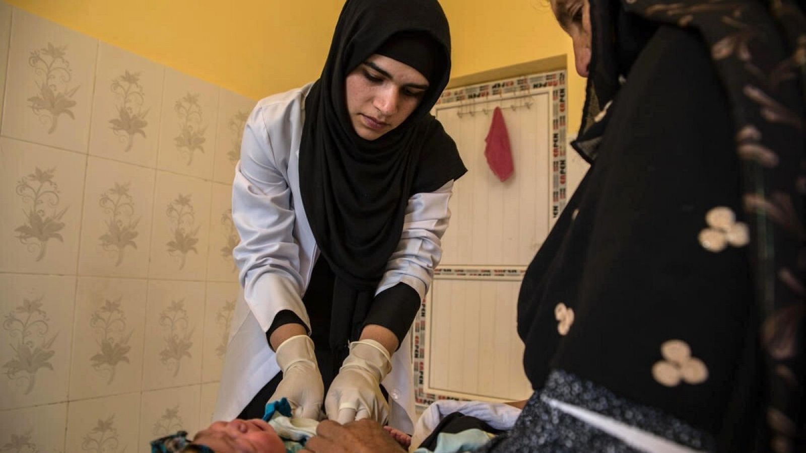 Una mujer afgana atiende a una madre y su bebé en una clínica en una aldea próxima a Herat, en Afganistán
