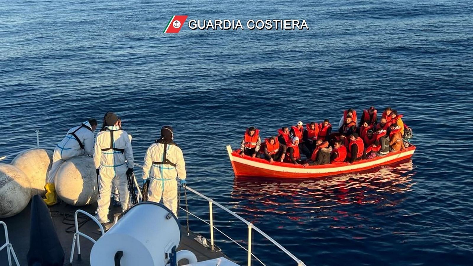 Guardacostas en un barco y migrantes en una pequeña embarcación durante una operación de rescate en curso en Siracusa