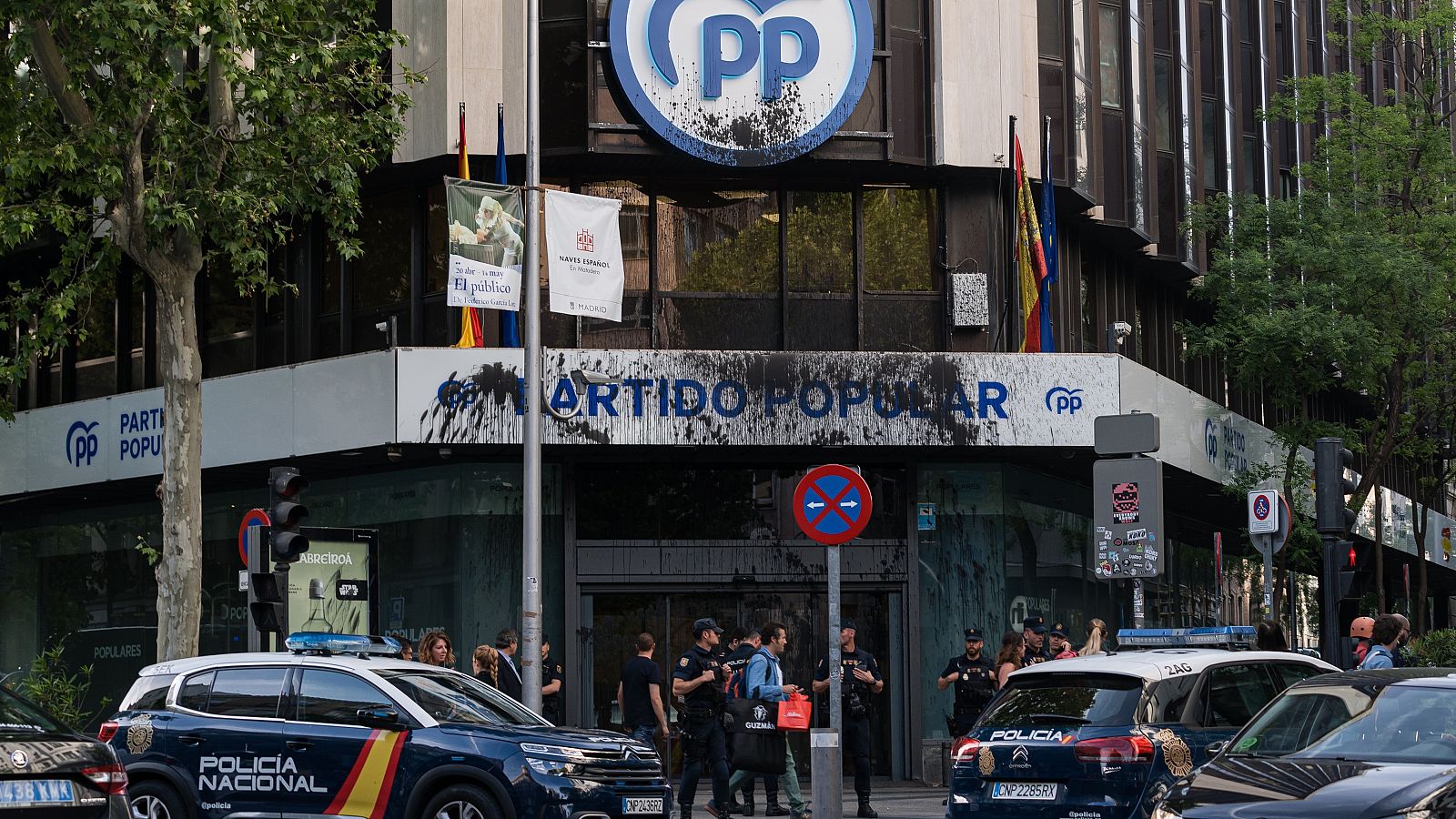 Agentes de la policía nacional frente a la fachada de la Sede del Partido Popular en la calle Génova. La fachada está manchada de pintura negra.