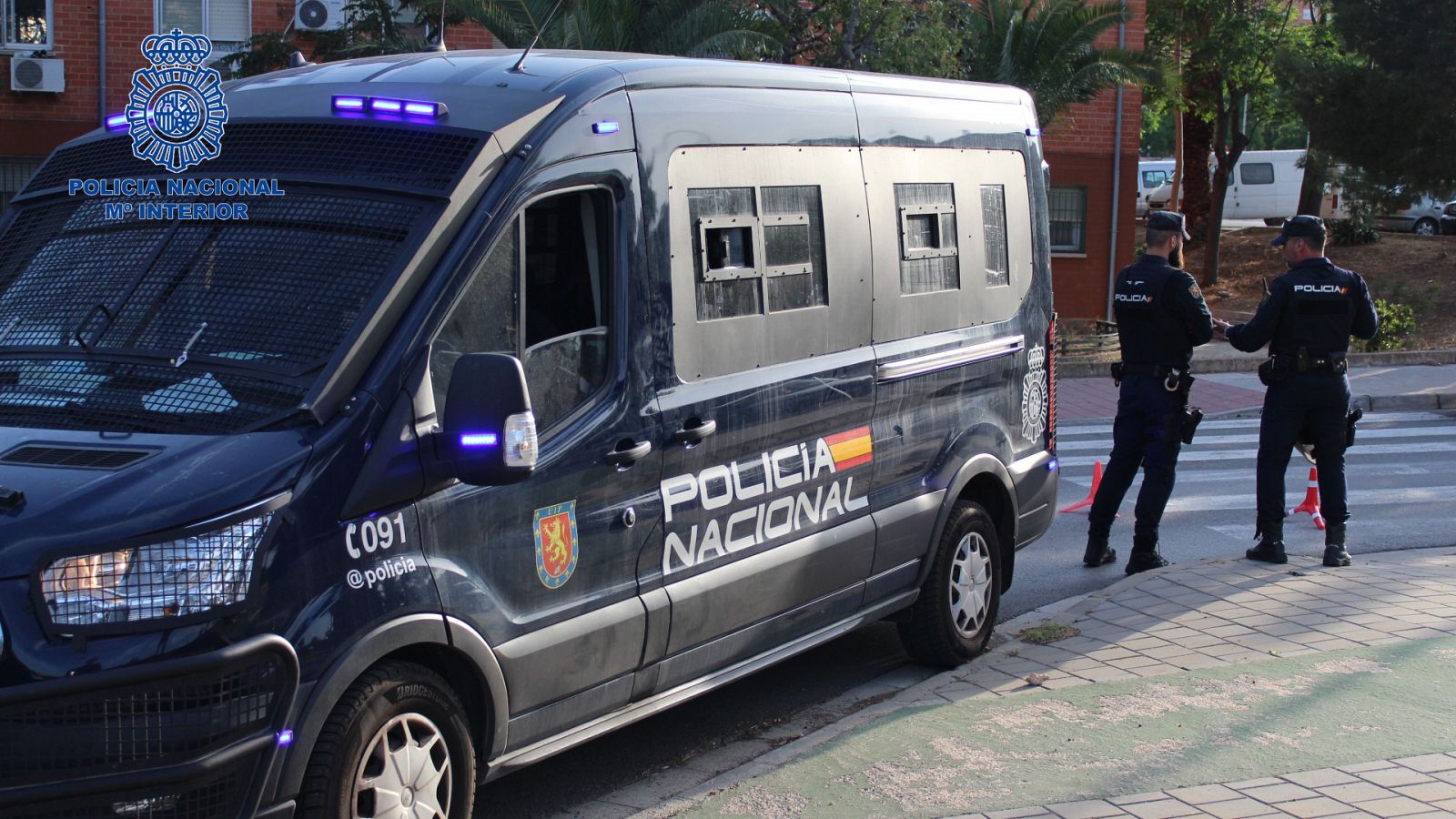 Dos agentes esperan frente a un vehículo de la Policía Nacional.