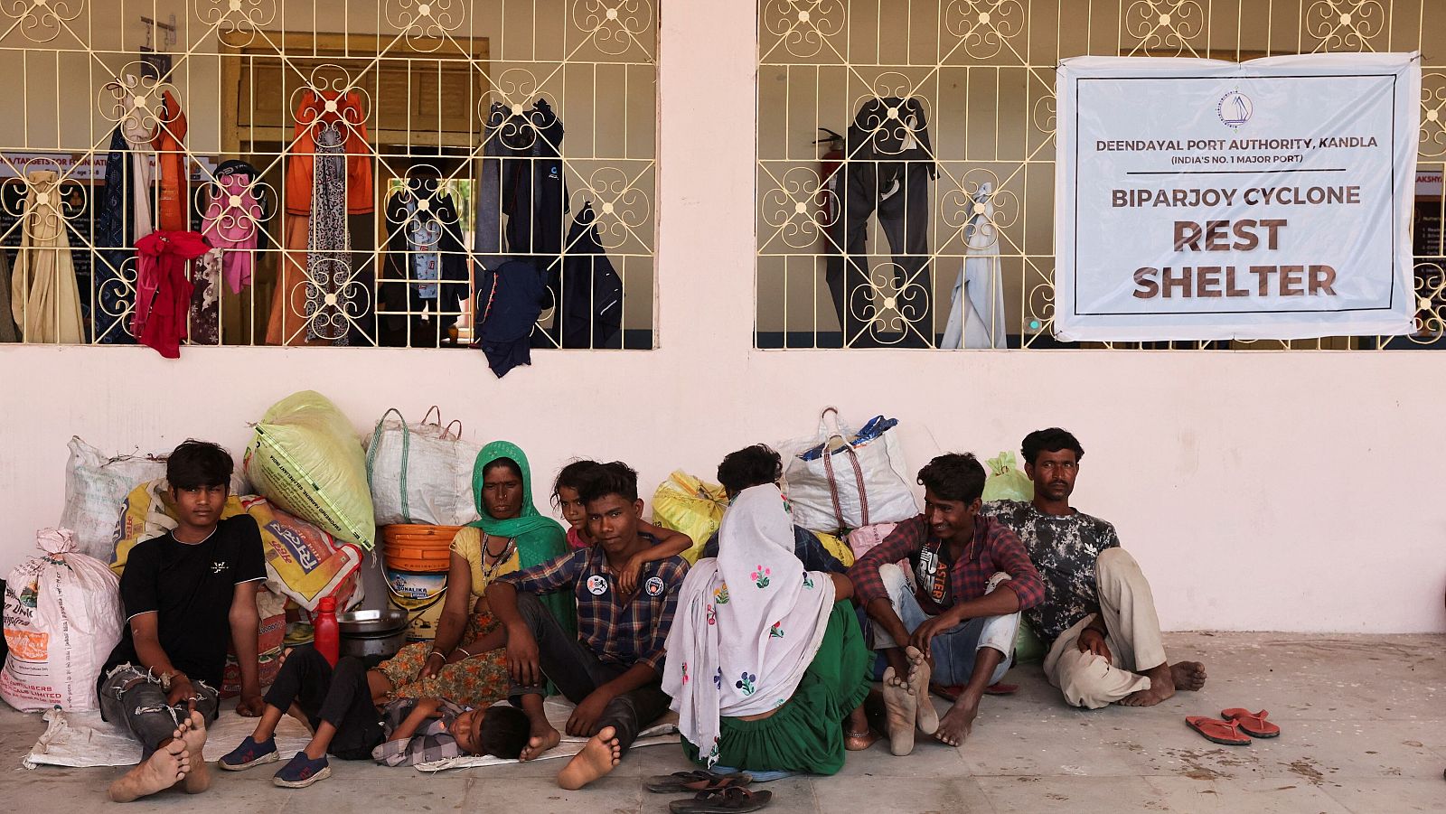 Personas evacuadas del puerto de Kandla sentadas frente a una escuela convertida en refugio en Gandhidham, en el estado occidental de Gujarat, ante la llegada del ciclón Biparjoy