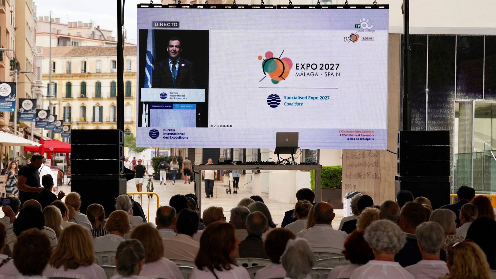 Público con camisetas en apoyo de la candidatura de la Expo Málaga 2027, asisten en la calle Alcazabilla de la ciudad andaluza a la retransmisión en directo de la Asamblea del BIE. Foto: Álex Zea / Europa Press