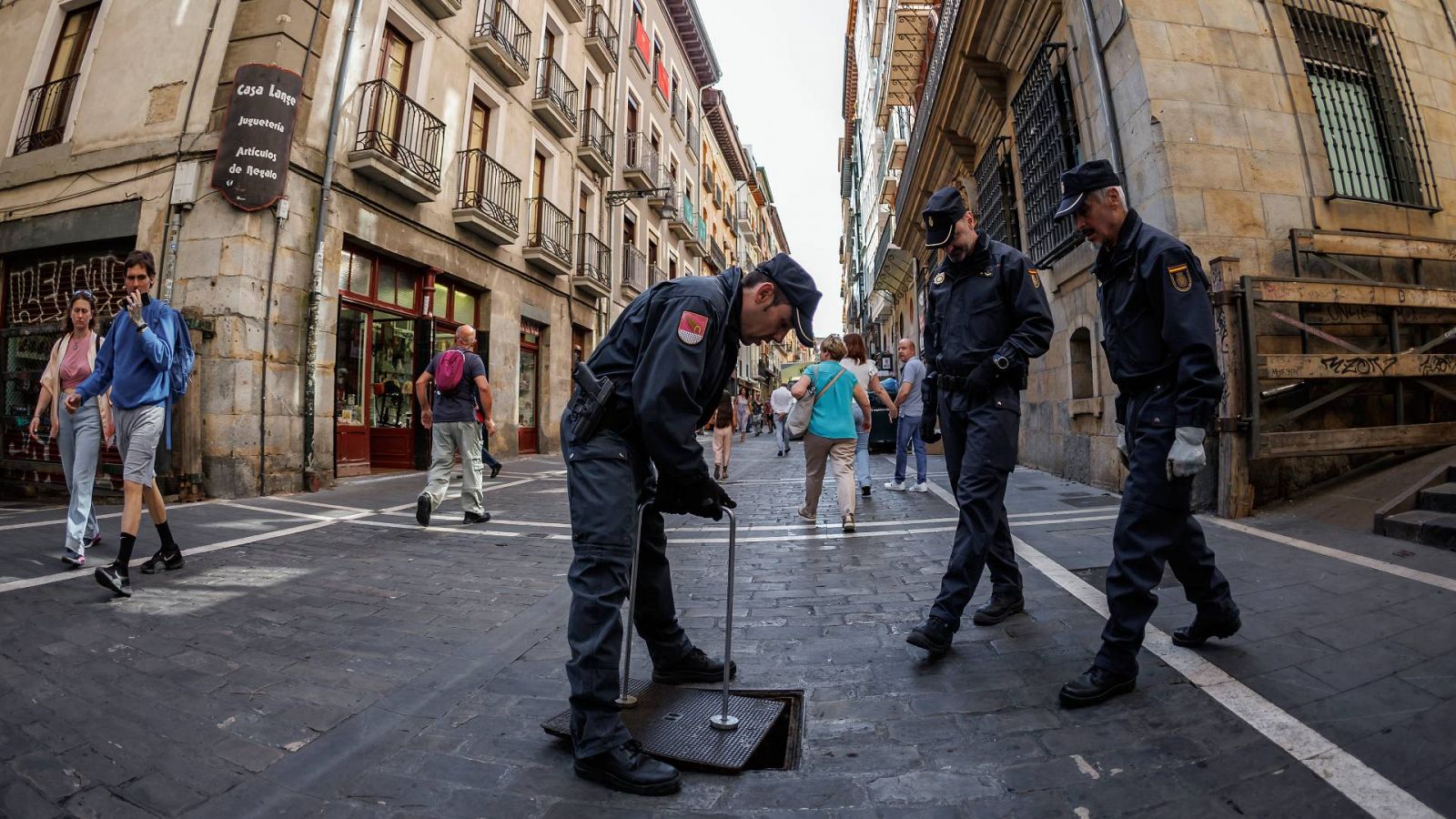 Efectivos de la Policía Nacional cierran la tapa de acceso de la calle Estafeta al alcantarillado antes de San Fermín 2022