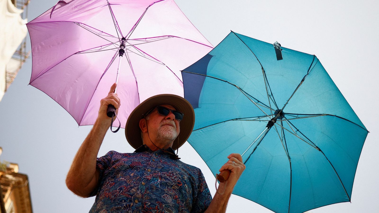 ¿Es normal el calor que está haciendo este verano?: Un hombre usa dos paraguas para protegerse del sol en Roma, Italia