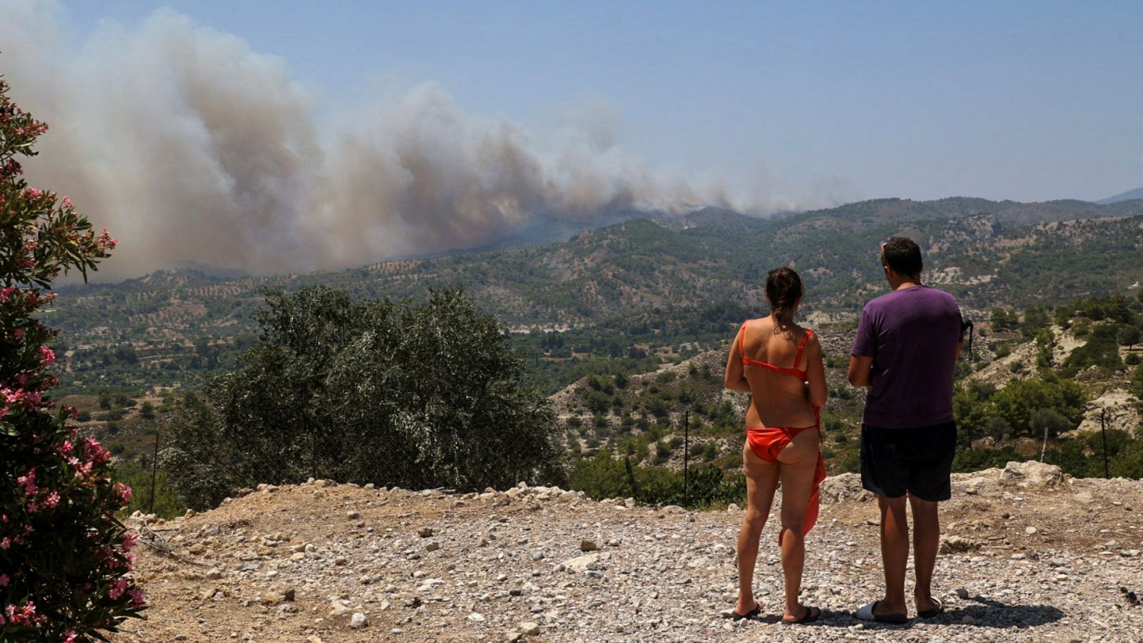 Dos turistas observan las llamas desde la lejanía en Archangelos, en la isla de Rodas.