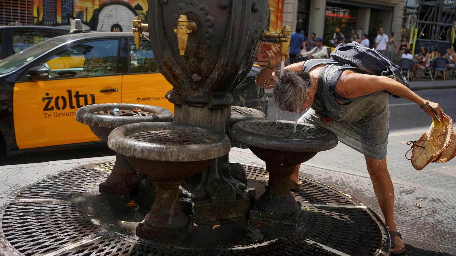 Una mujer se refresca en una fuente de Las Ramblas de Barcelona.