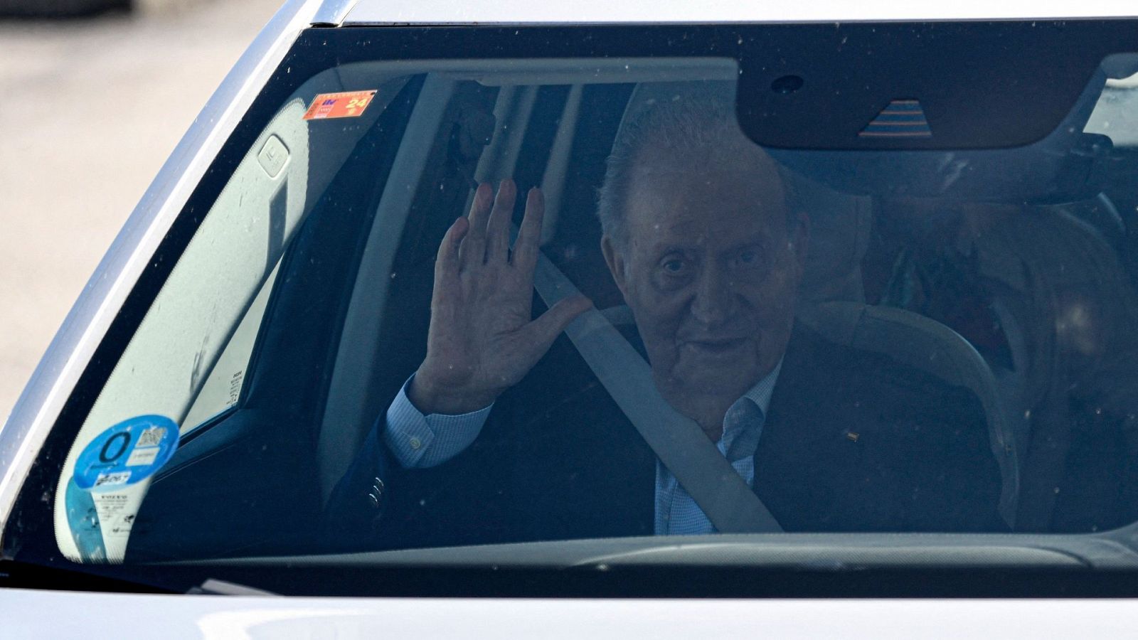 El rey emérito saluda desde el coche a su salida del aeropuerto de Vigo