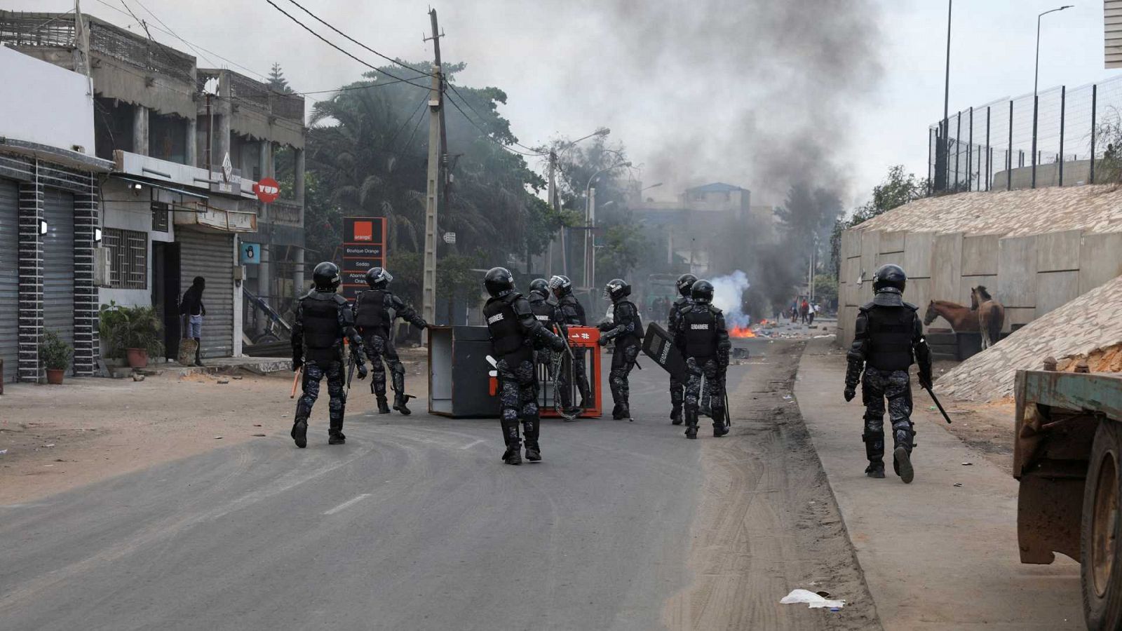 Las fuerzas de seguridad de Senegal retiran un quiosco volcado por manifestantes para bloquear una carretera en Dakar tras la detención de Ousmane Sonko.