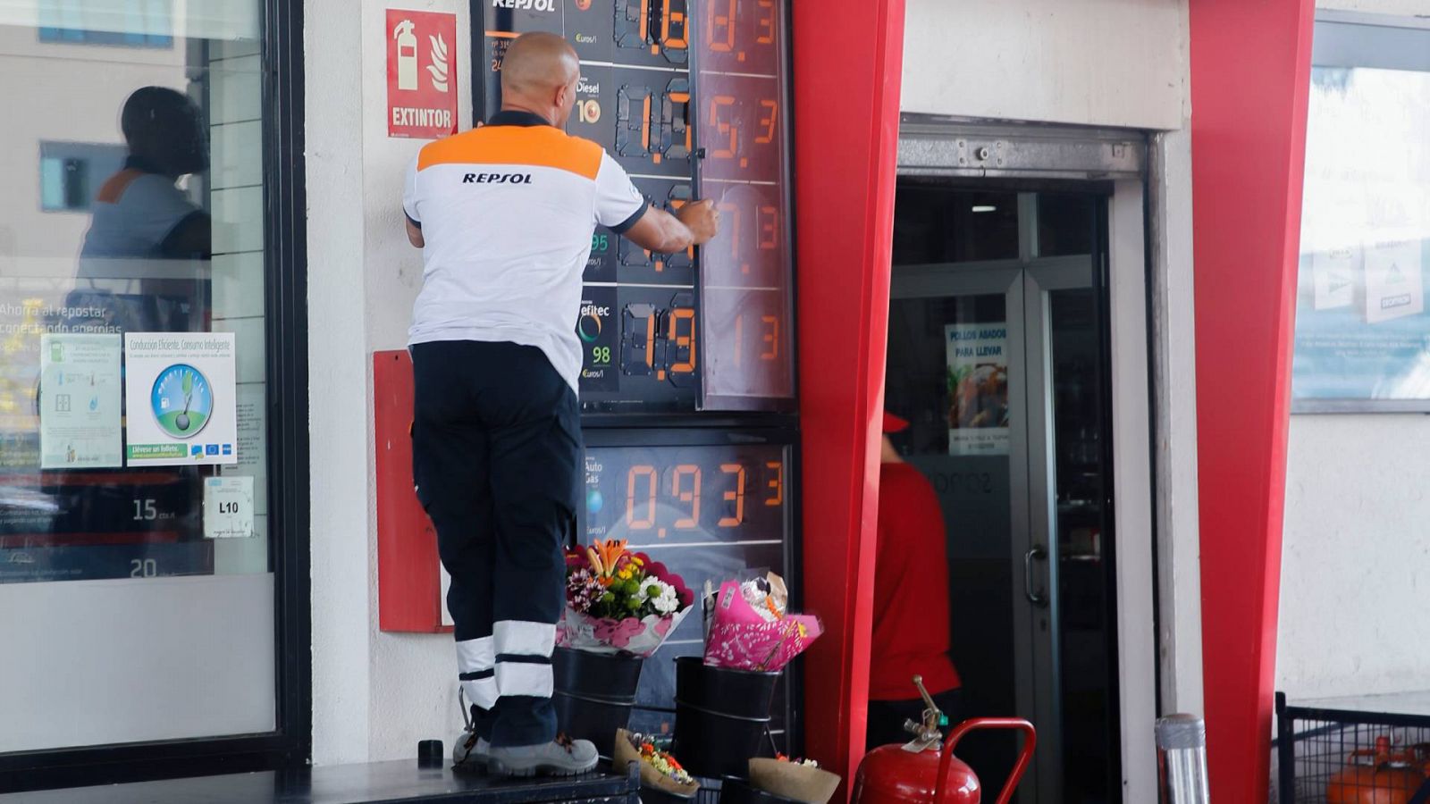 Un trabajador cambia los precios de los carburantes en un panel de una gasolinera de Madrid