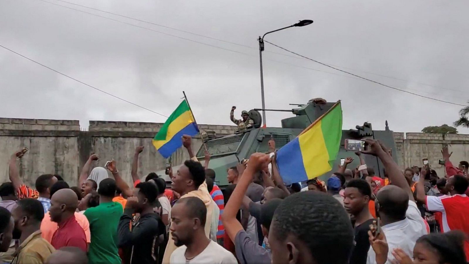 Un vehículo militar pasa al lado de personas que celebran el golpe de Estado en Gabón