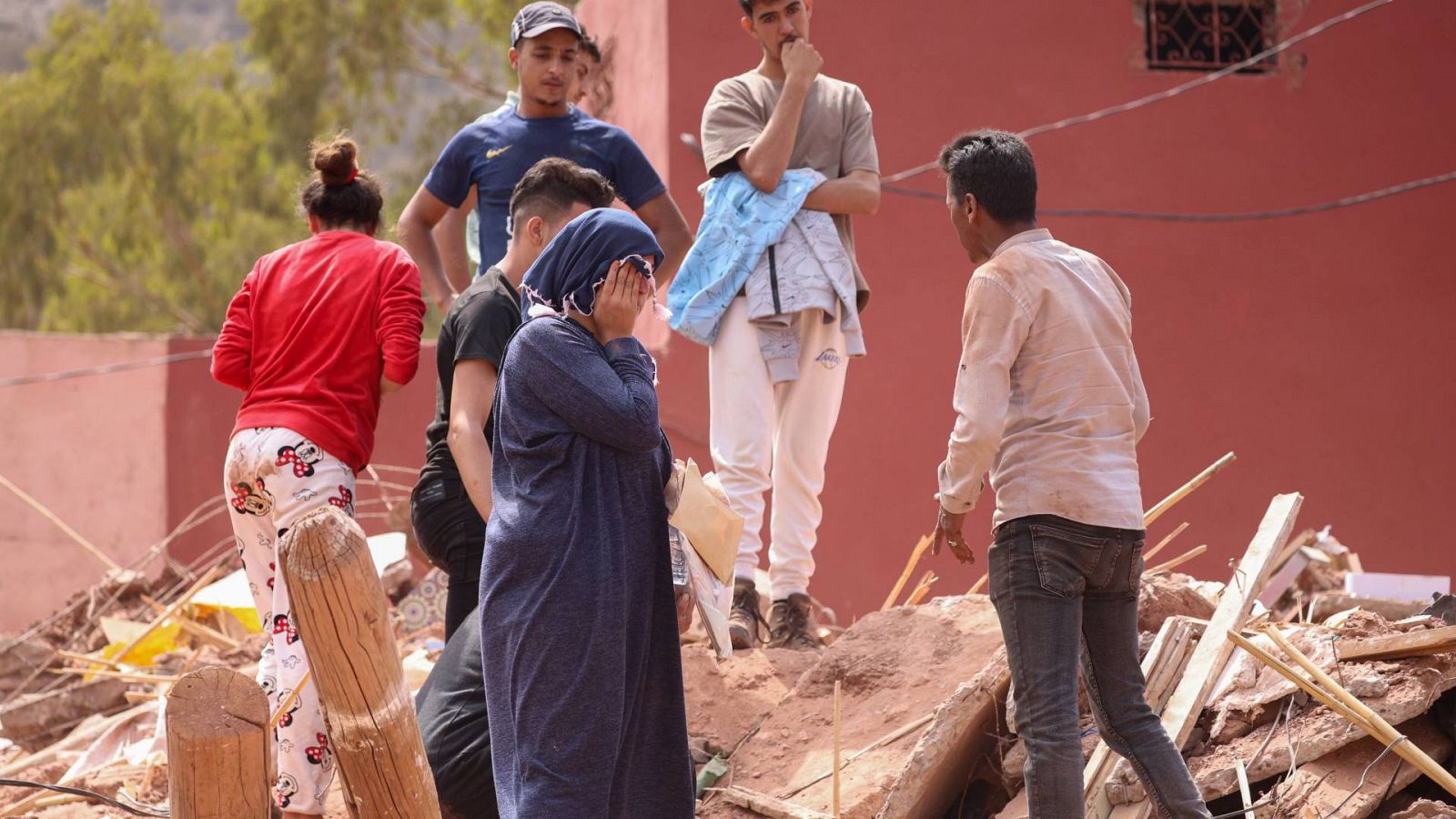 Los familiares de una víctima del terremoto en Marruecos permanecen sobre las ruinas de una casa en Ouirgane.