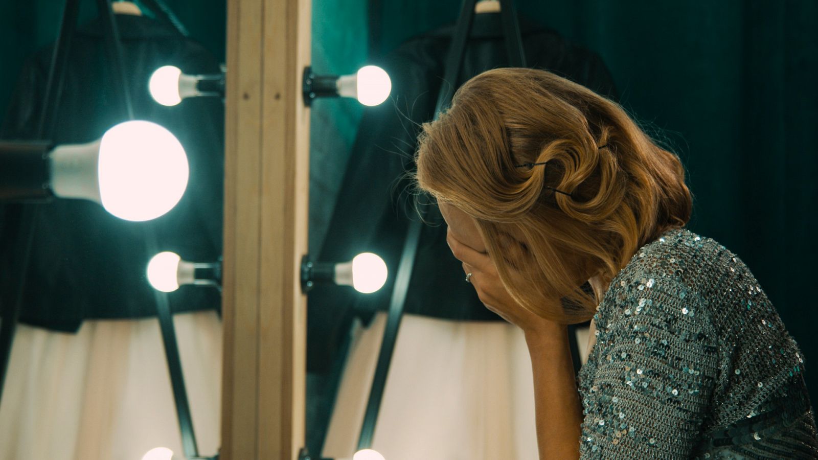 Una actriz se cubre el rostro con las manos frente a un espejo