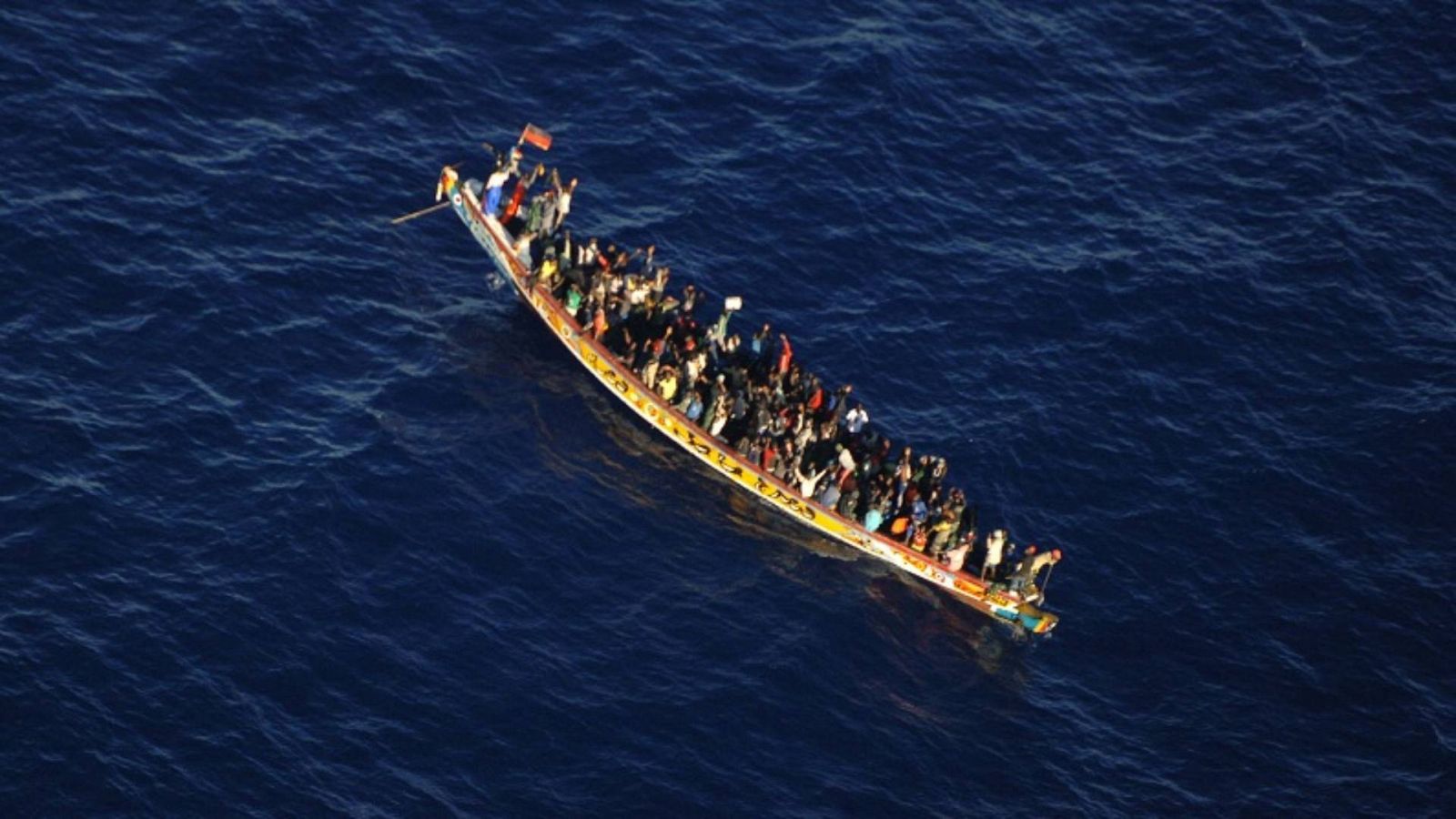 Imagen de un cayuco con varias personas migrantes a bordo en la costa canaria