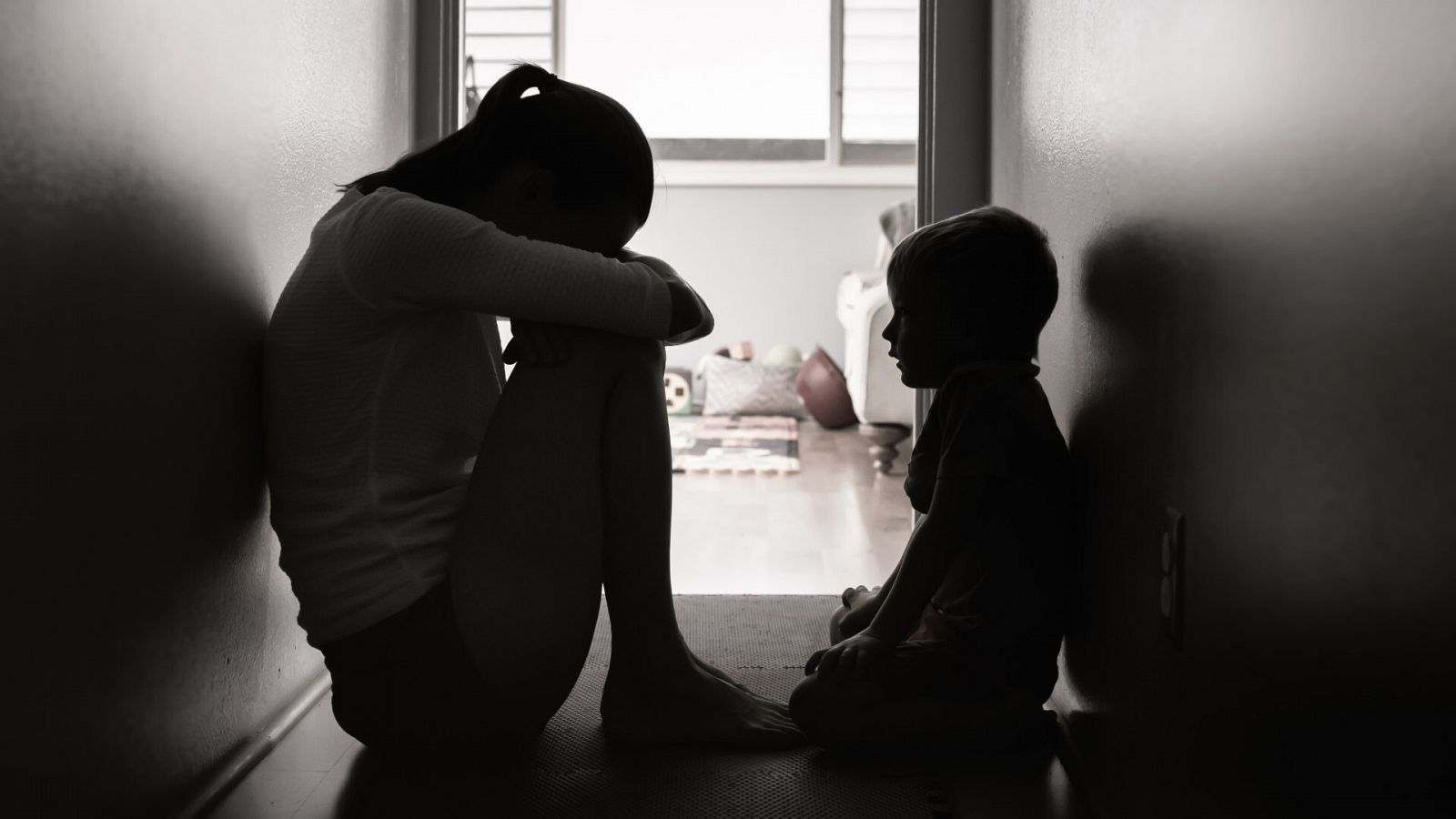 Prevención de la violencia vicaria: Una mujer llora acurrucada en un pasillo junto a un niño, en una imagen de archivo.
