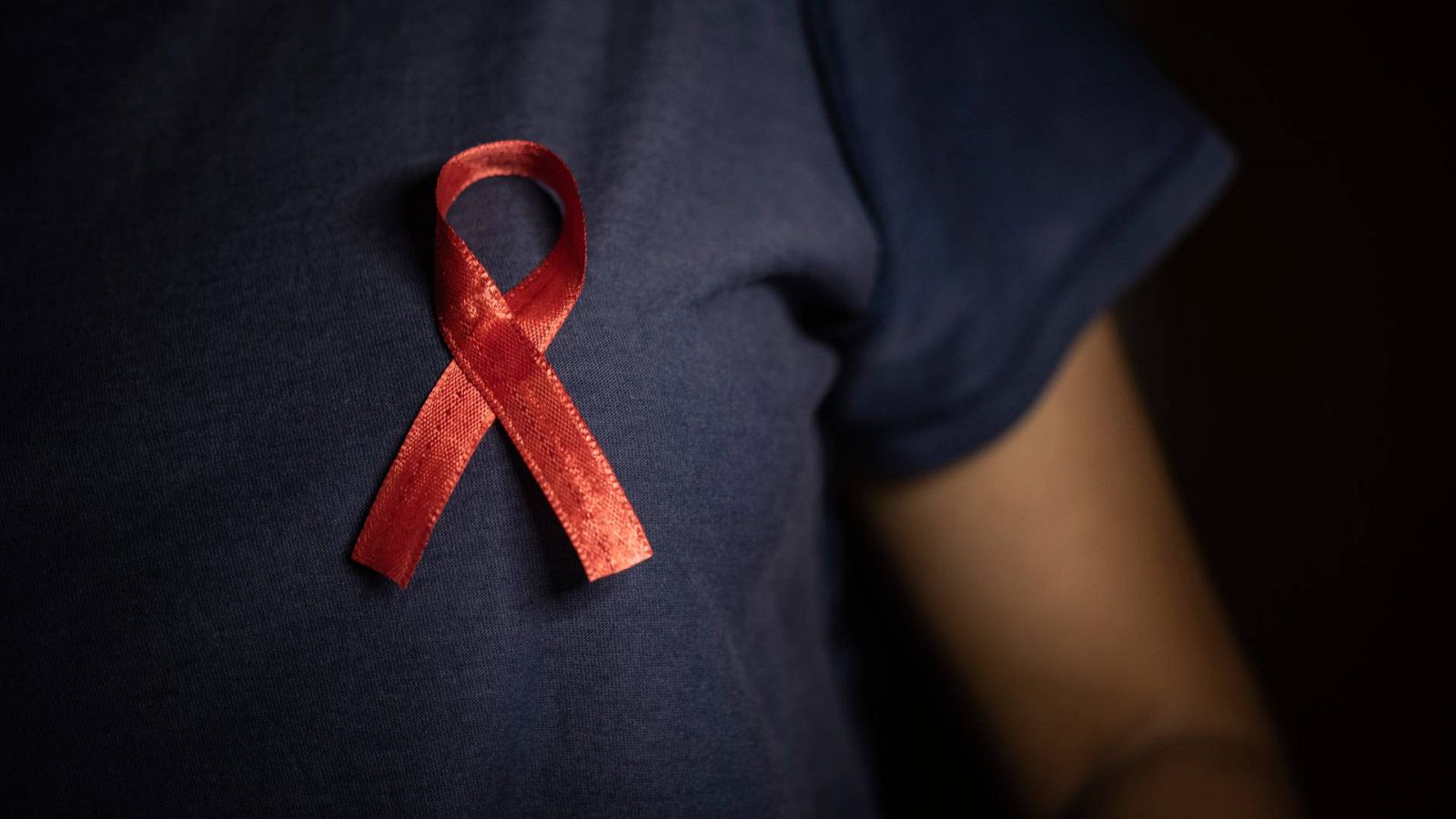 Una persona con un lazo rojo, símbolo de la lucha contra el VIH