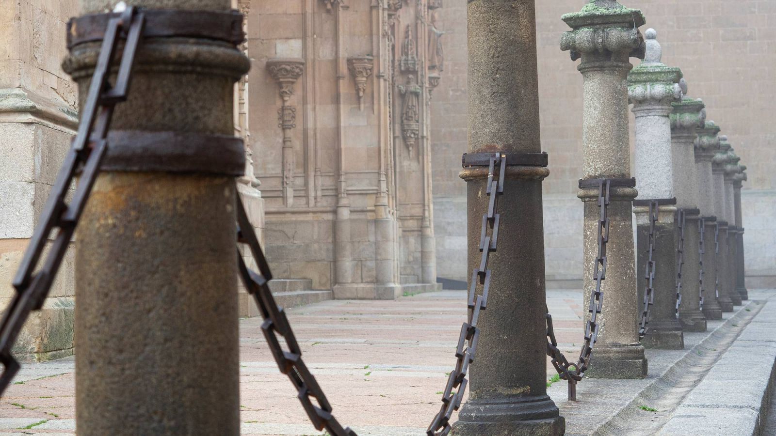 Cadenas sostenidas por bolardos, un día de niebla, en el exterior de la Catedral de Salamanca