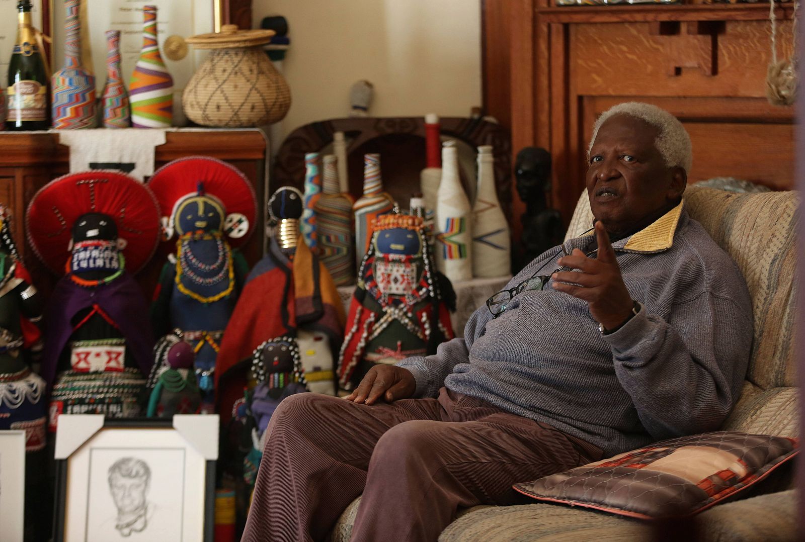 El fotoperiodista Peter Magubane sentado en el sofá de su casa en Johannesburgo