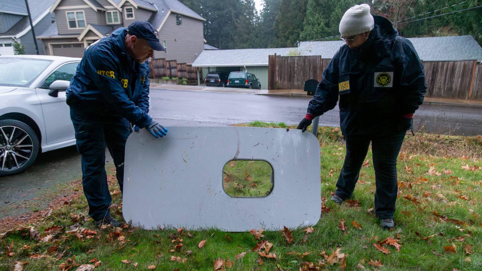 Dos agentes inspeccionan la puerta del avión de Alaska Airlines que perdió parte del fuselaje en pleno vuelo