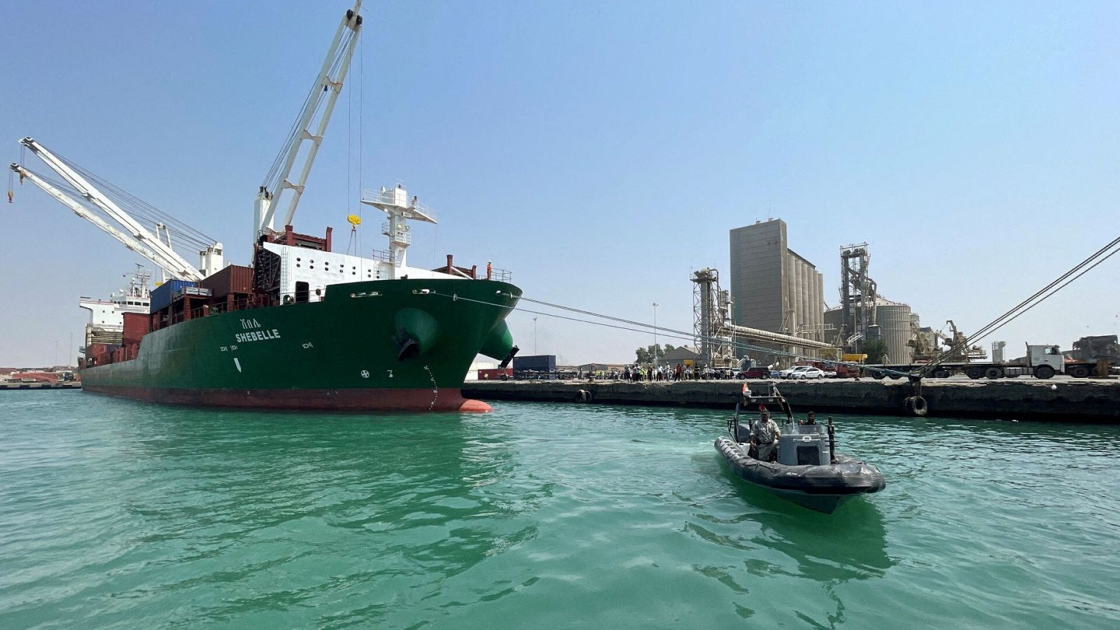 Un barco de guardacostas navega junto a un portacontenedores comercial atracado en el puerto de Hodeidah, en el Mar Rojo, en Yemen.