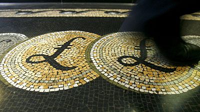 Una persona camina sobre un mosaico con el símbolo de la libra siutado en la entrada del Banco de Inglaterra