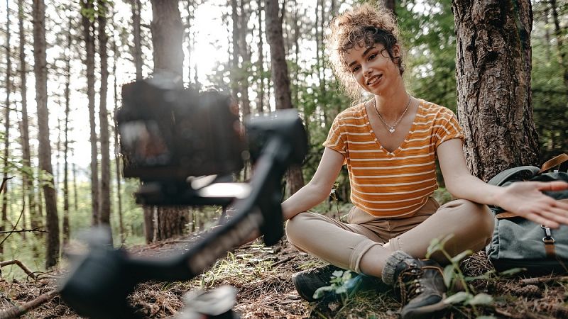 Una joven se graba con su cámara en un bosque