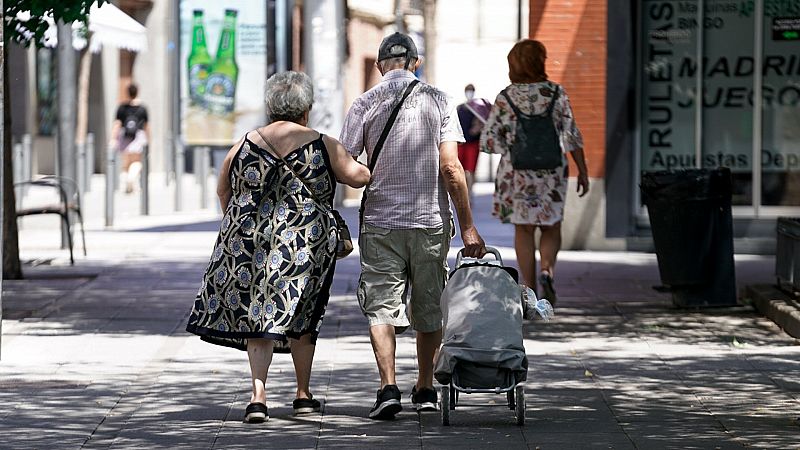 Una pareja de ancianos camina por las calles de Madrid con el carro de la compra