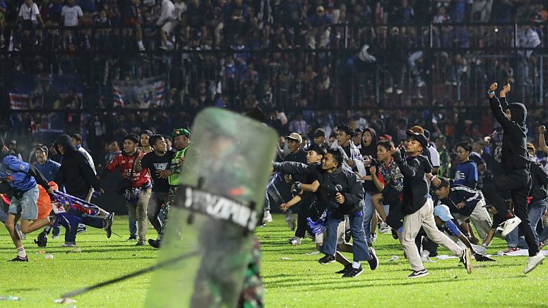 Aficionados al fútbol entran en el campo durante un enfrentamiento entre hinchas en el estadio Kanjuruhan en Malang, Indonesia.