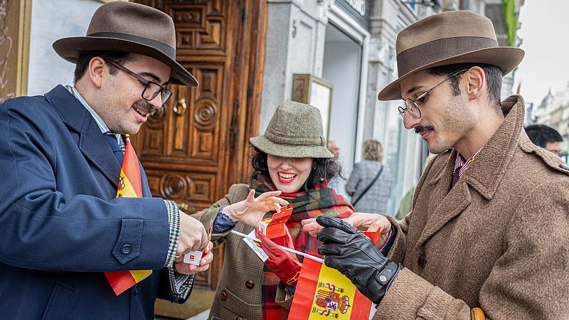 Ciudadanos con banderas de España comen pasteles conmemorativos en la Puerta del Sol a la espera del paso de la familia real en la jura de la Constitución de la princesa Leonor.