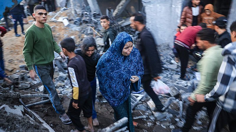 Ciudadanos palestinos caminan sobre los daños ocasionados por un bombardeo israelí en el sur de Gaza