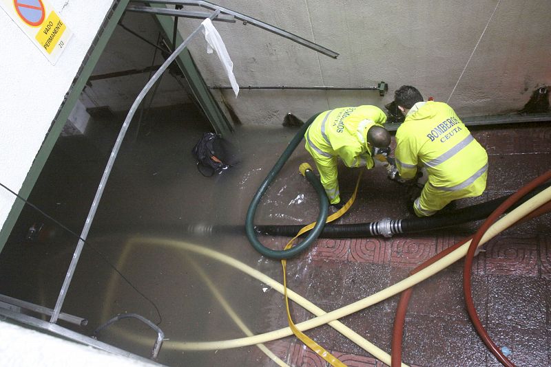 Dos bomberos quitan el agua de un bajo en Ceuta