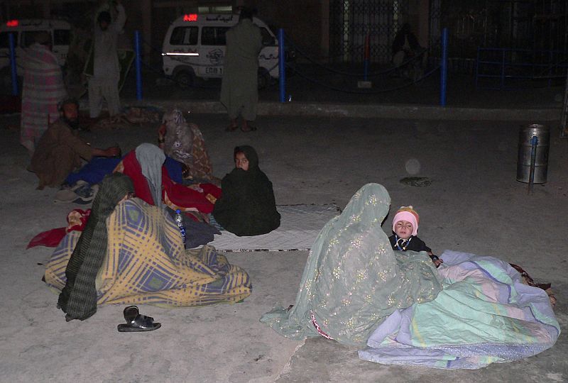 Residents sit outside their homes as an earthquake jolts the city of Quetta