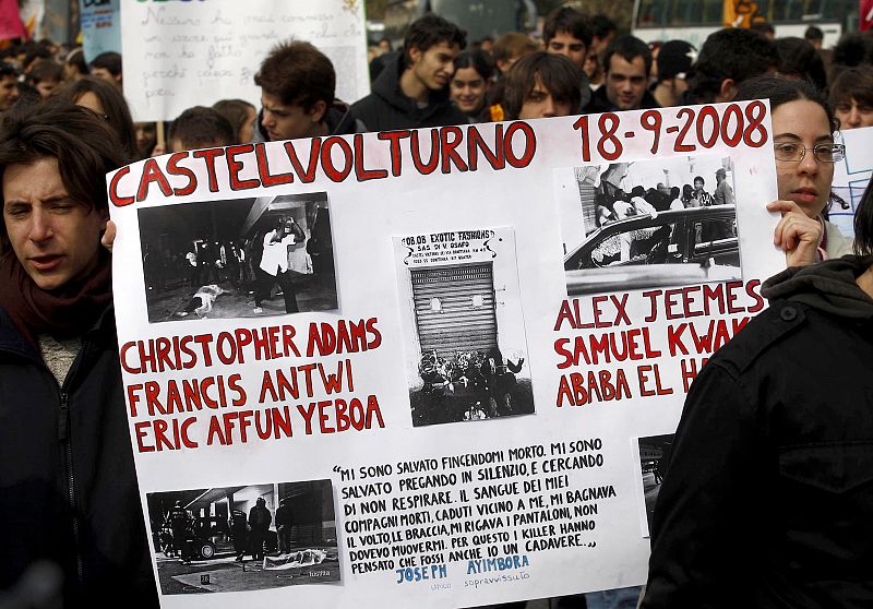 Demonstrators hold a banner remembering the massacre of Castelvolturno as they march in the southern city of Naples