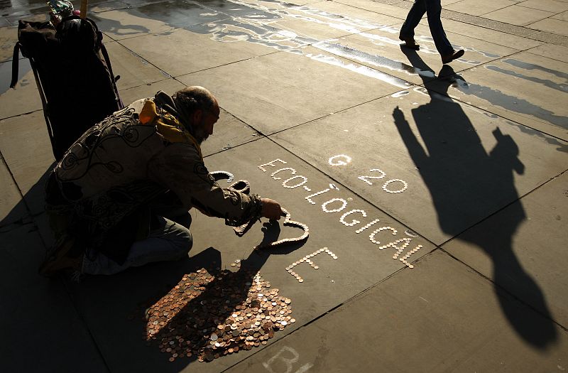 Un activista escribe un mensaje contra el G-20 con monedas en Trafalgar Square