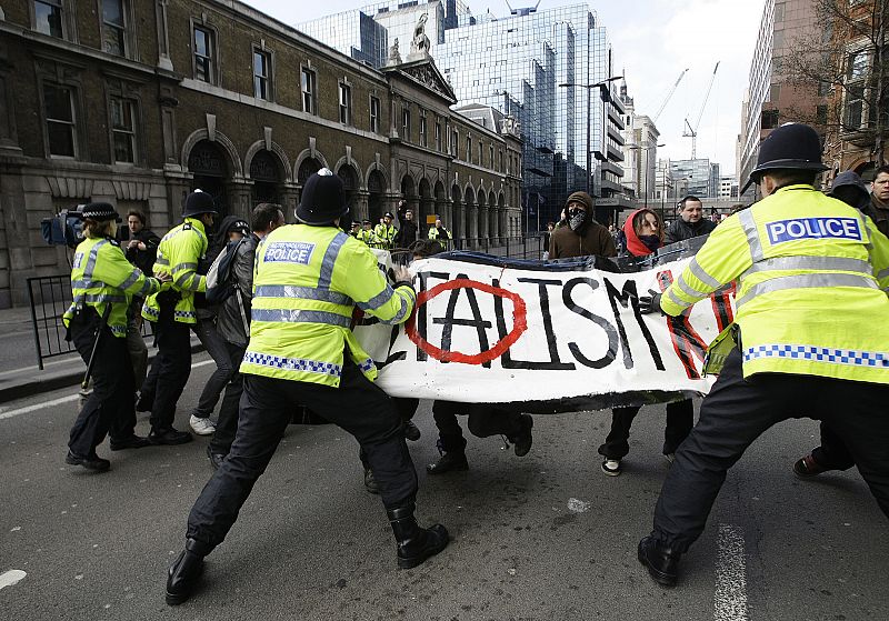 Policías forcejean con activistas en el distrito financiero de la capital británica.