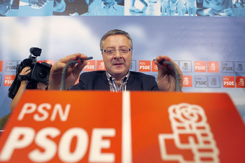PSOE coordinator Blanco adjusts microphones before news conference in Pamplona