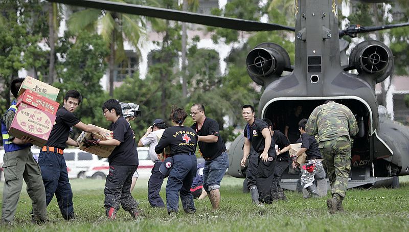 Voluntarios transportan provisiones a un helicóptero militar que vuela a los pueblos afectados a dejarles víveres y recoger a los supervivientes