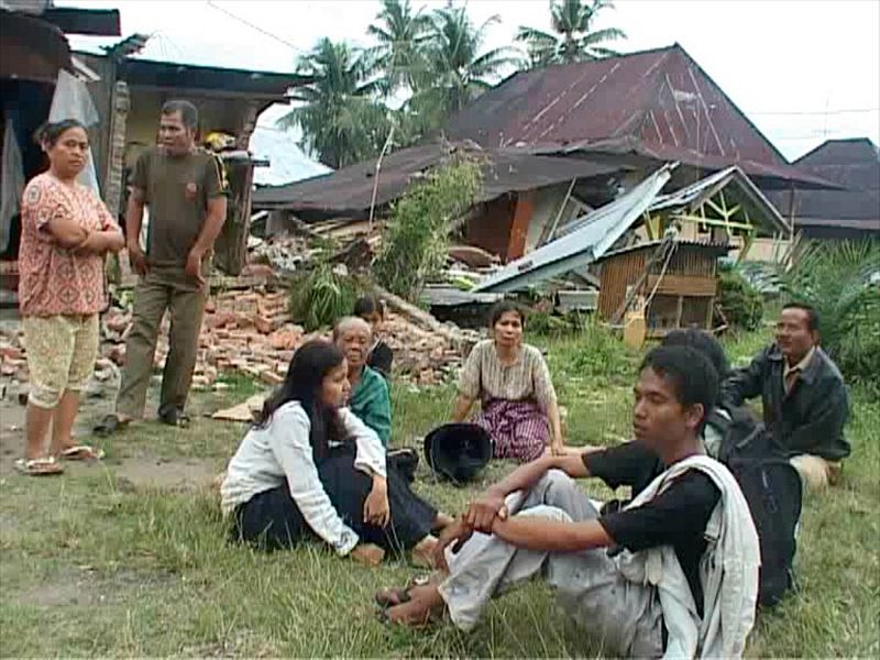 Residents wait outside damaged houses after an earthquake in Padang, Indonesia's Sumatra island