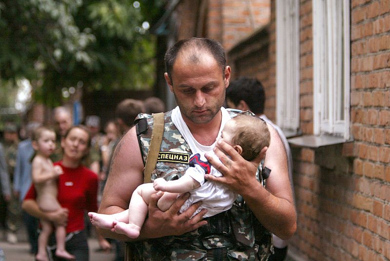 A Russian police officer carries a released baby from the school seized by heavily armed masked men ...