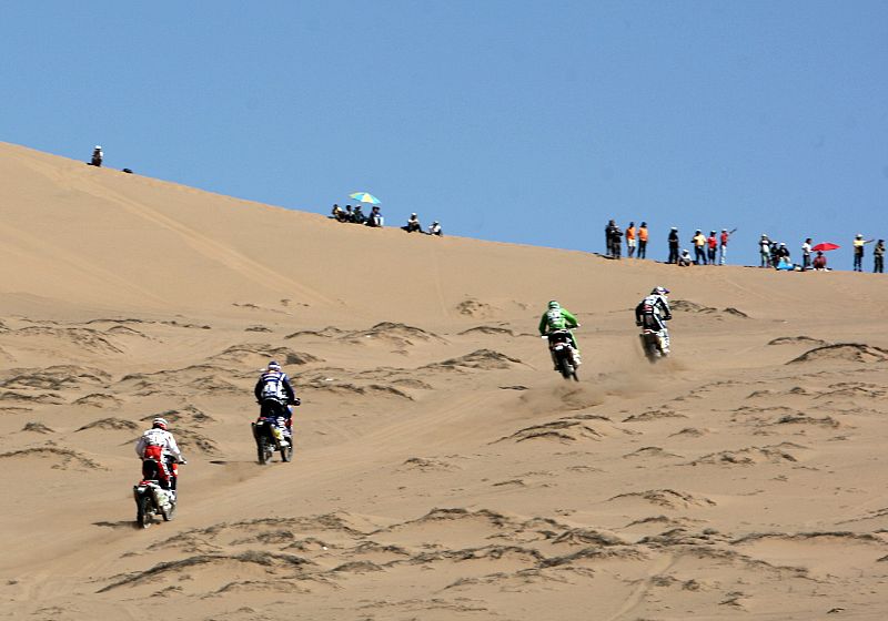Un grupo de motoristas asciende una duna a la salida de la etapa en Copiapó.