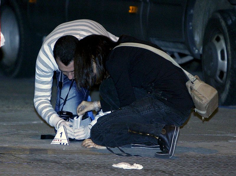 Dos agentes toman pruebas en el lugar donde dos mossos d'Esquadra han resultado heridos por arma de fuego, sobre las 23:30 horas del jueves en la calle Aragón de Barcelona.